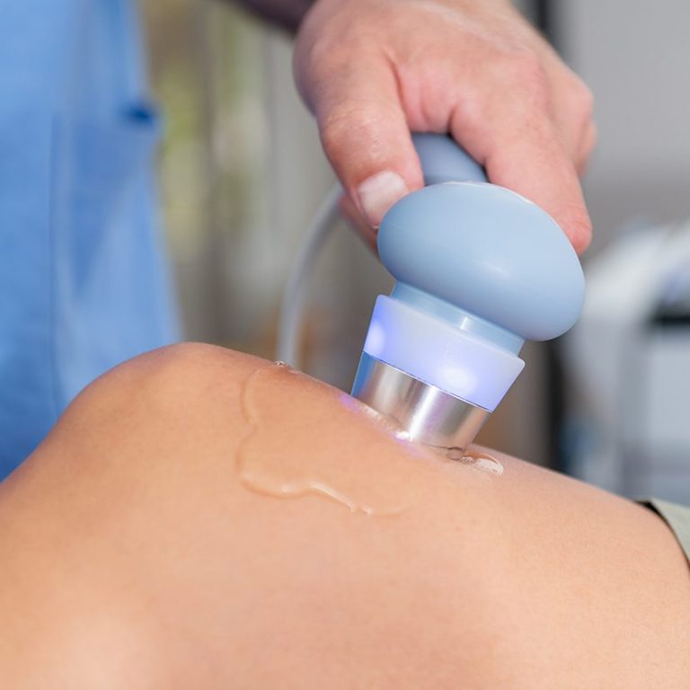 Hand, die ein Ultraschallgerät auf einer Hautstelle anwendet.